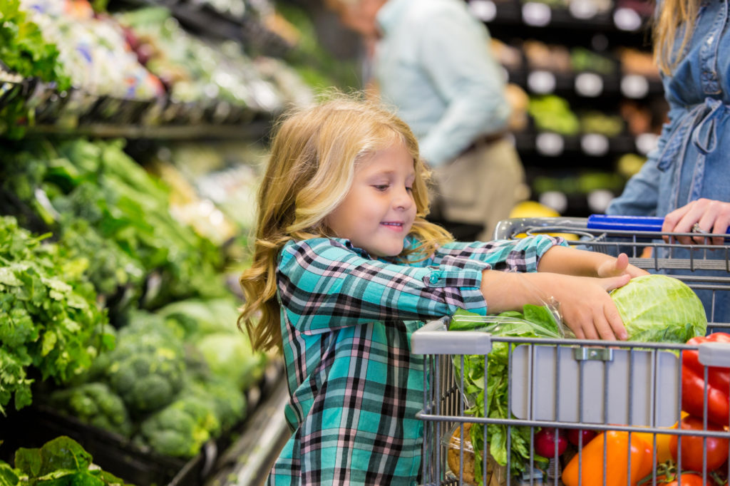 Little girl helping mother shop for produce in grocery store Purdue Extension Nutrition